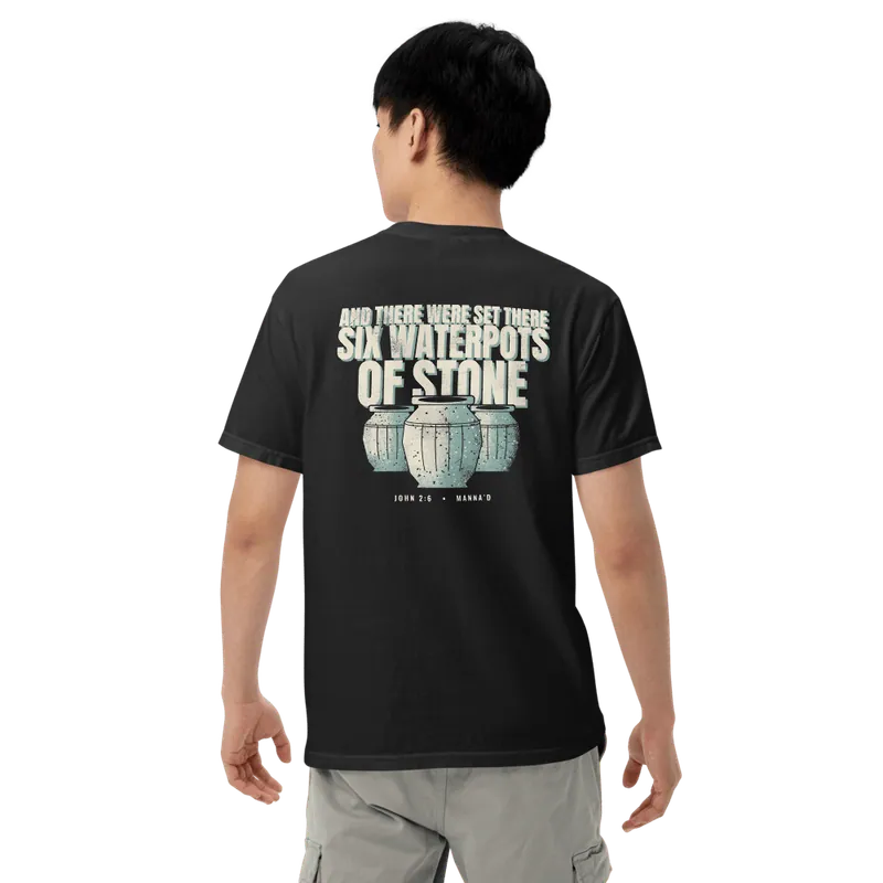 Back of a black Manna’d tee printed: AND THERE WERE SET THERE SIX WATERPOTS OF STONE (John 2:6)